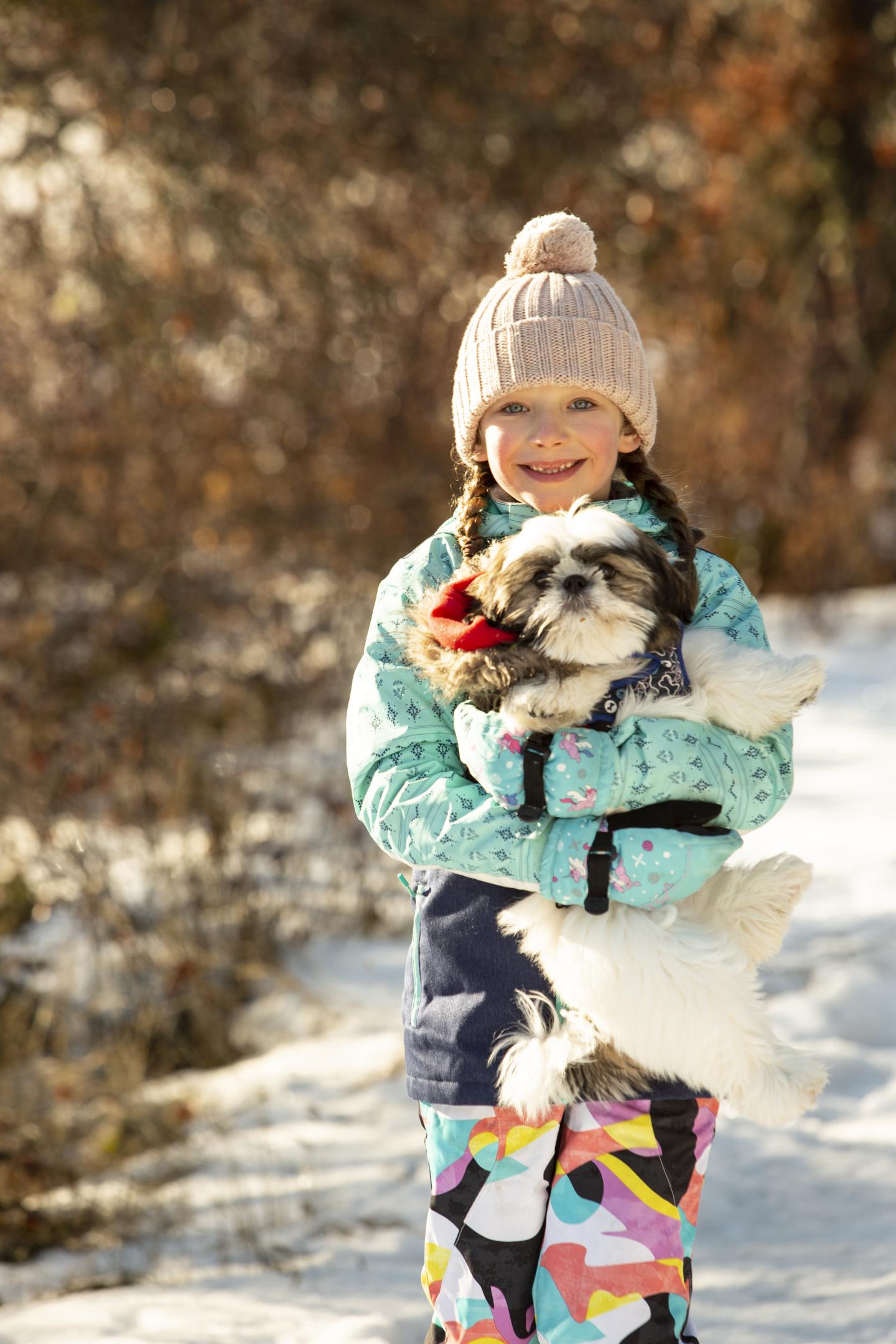 A child holding a dog in the snow