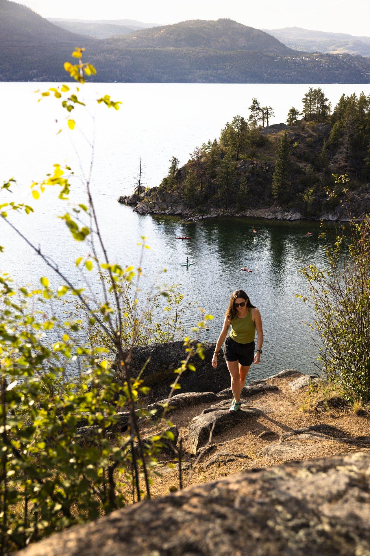 woman hiking above lake at sunset