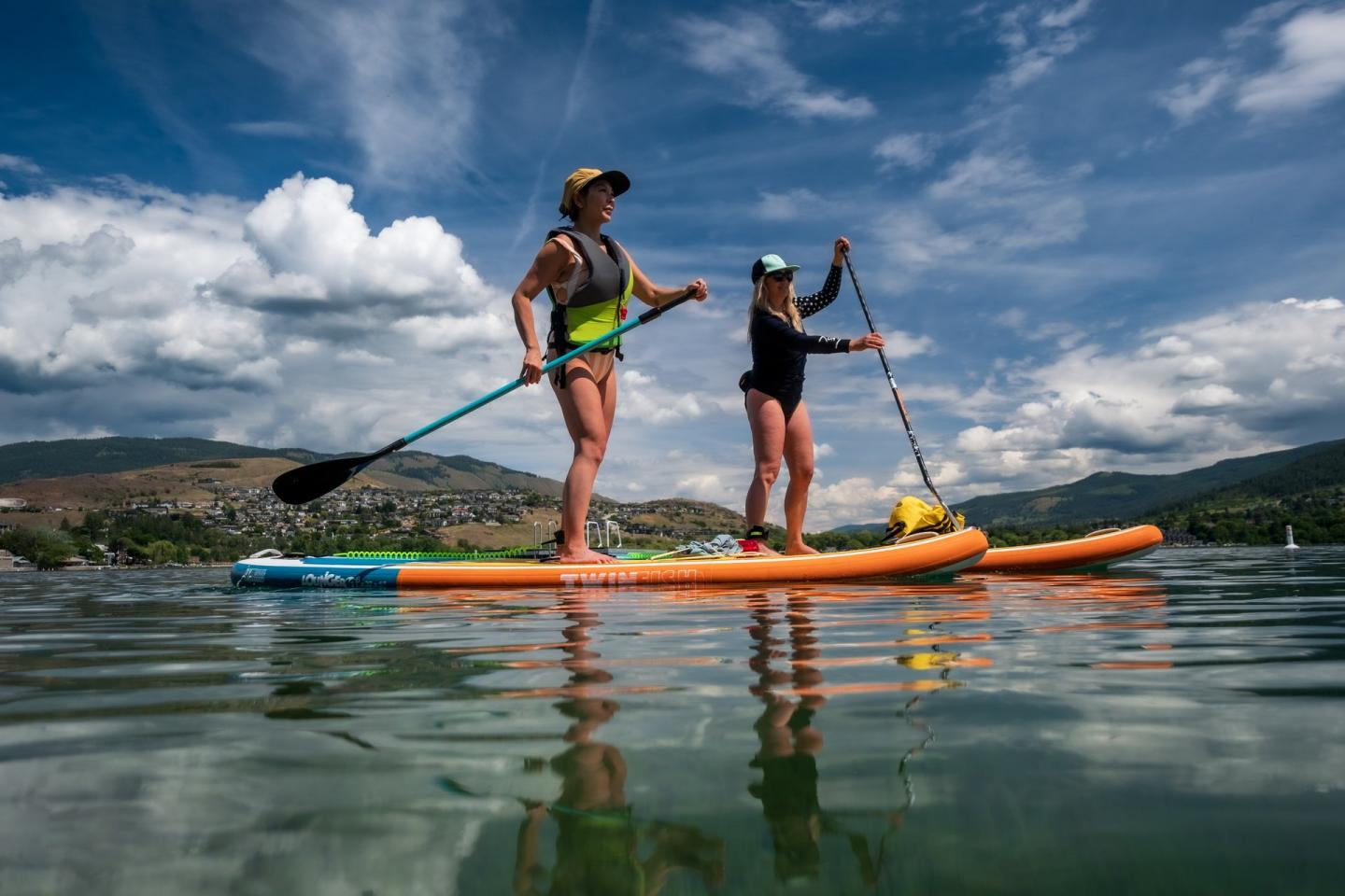 two women stand up paddleboarding on the lake