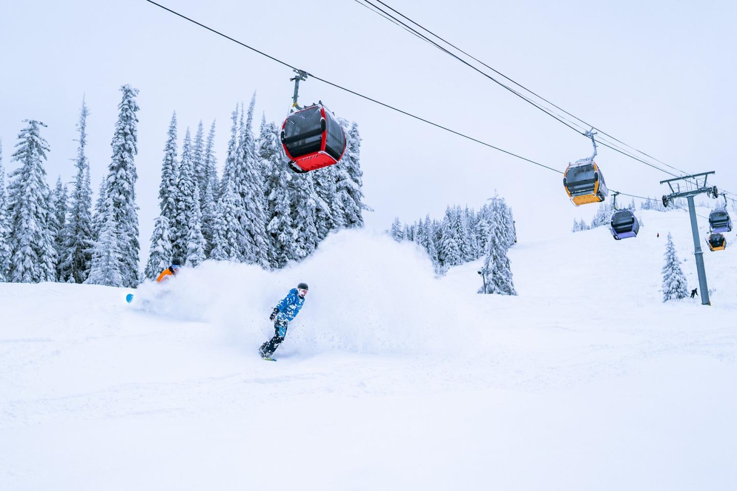 Person snowboarding in fresh snow under a gondola