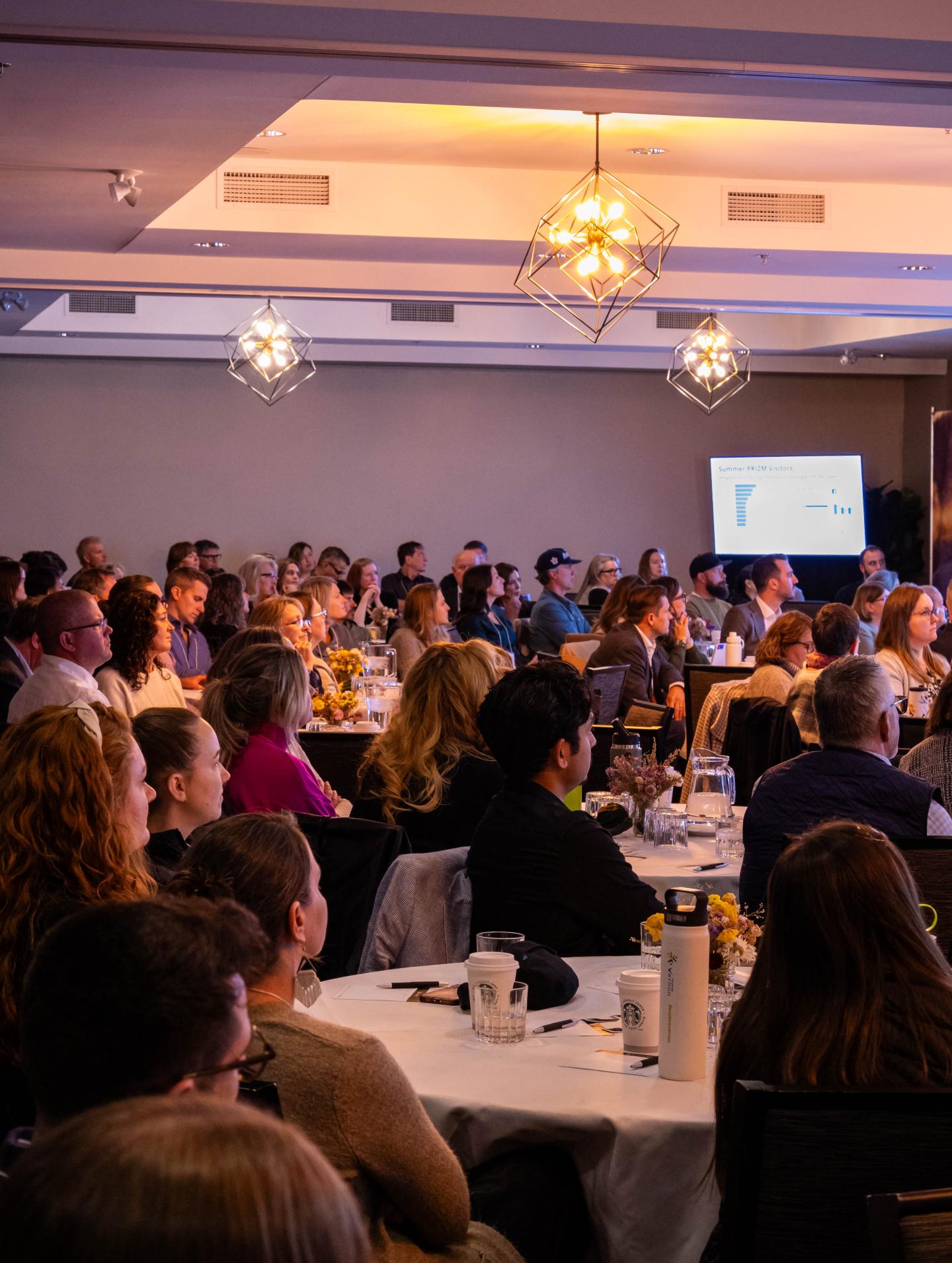 tables of people sitting around listening to a speaker at a conference