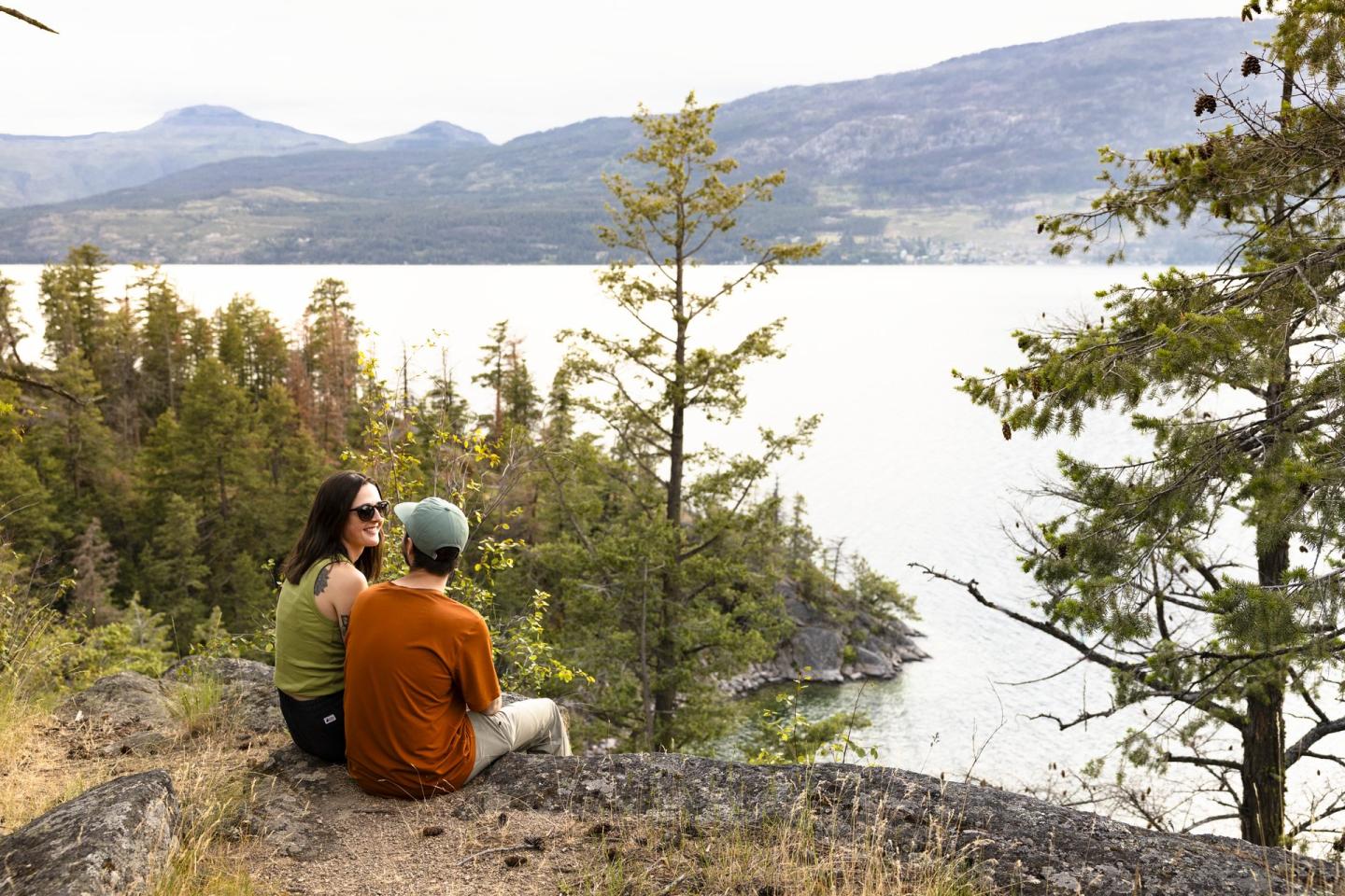 couple sitting on rock overlooking okanagan lake at ellison provincial park
