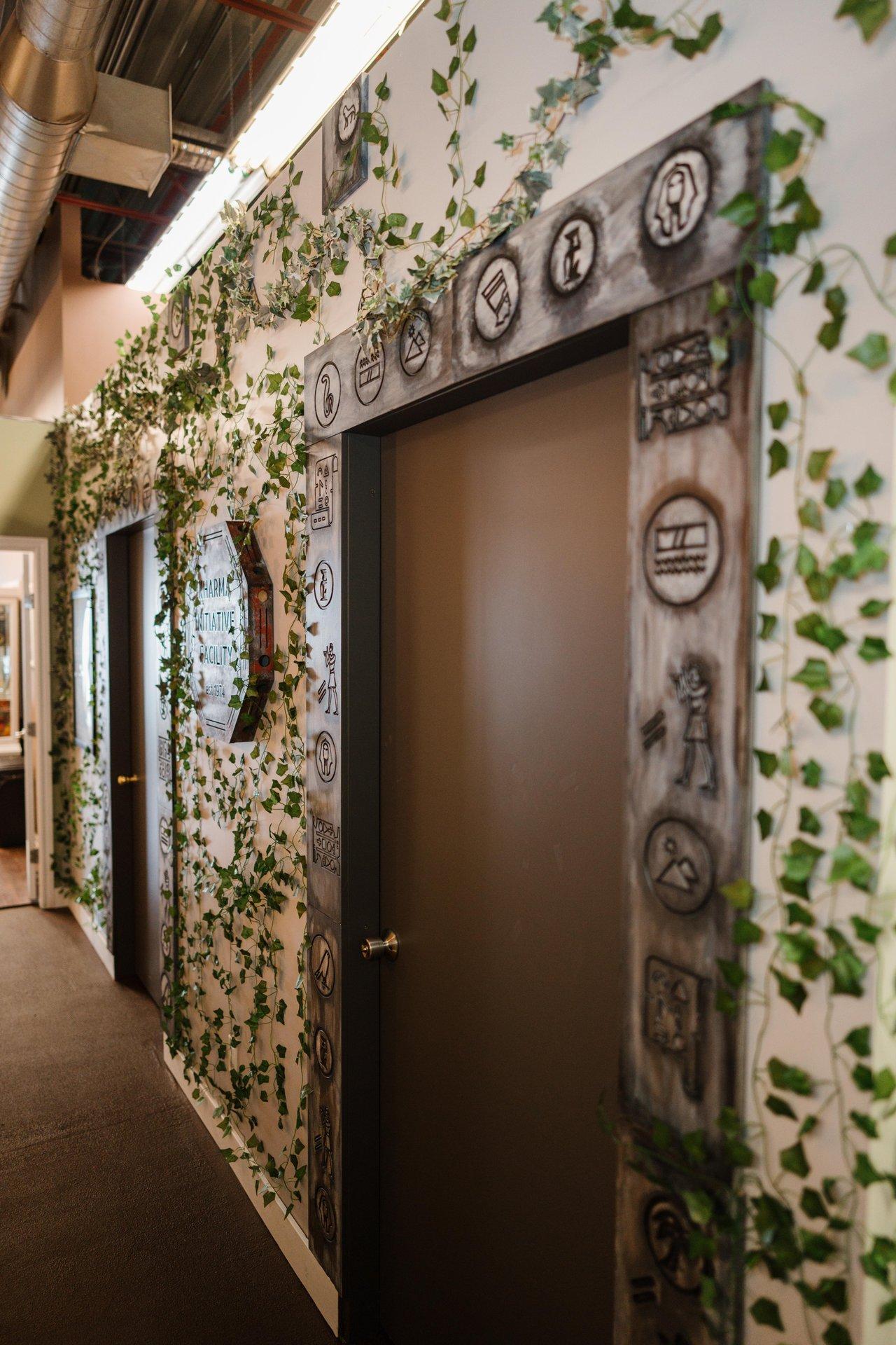 Beyond Belief escape room, hallway with vine-covered walls and brown doors.