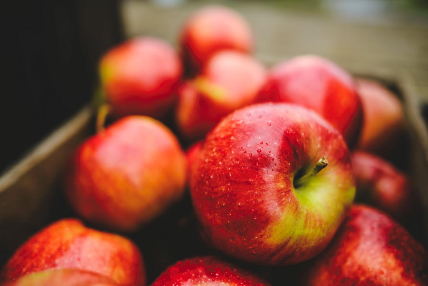Red apples piled in a wooden crate.