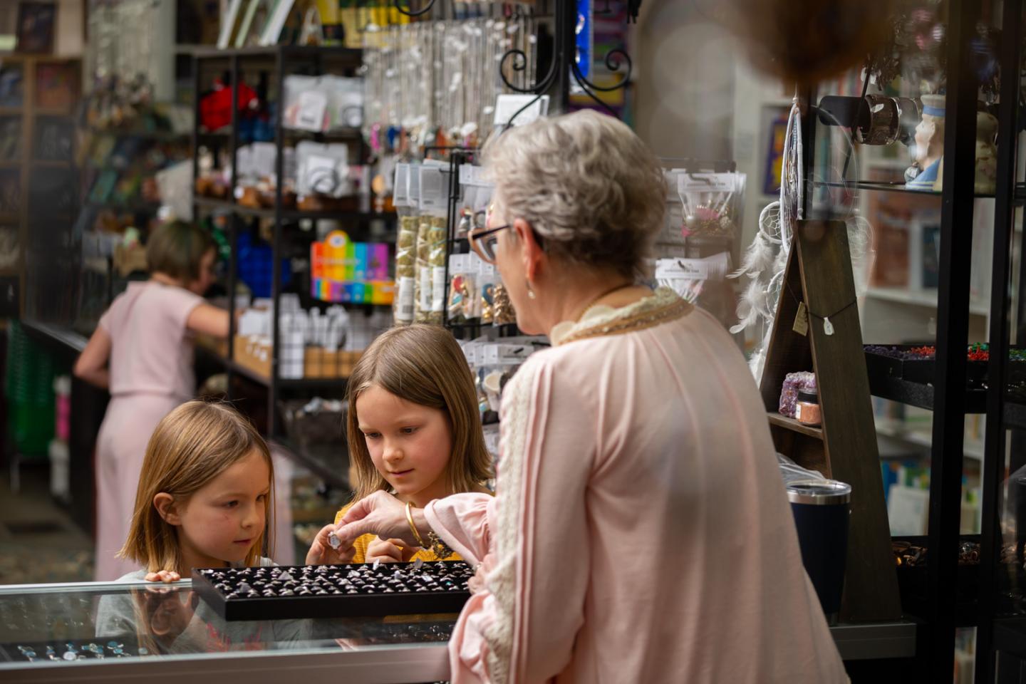 Older woman and two girls choosing chocolates in a store.