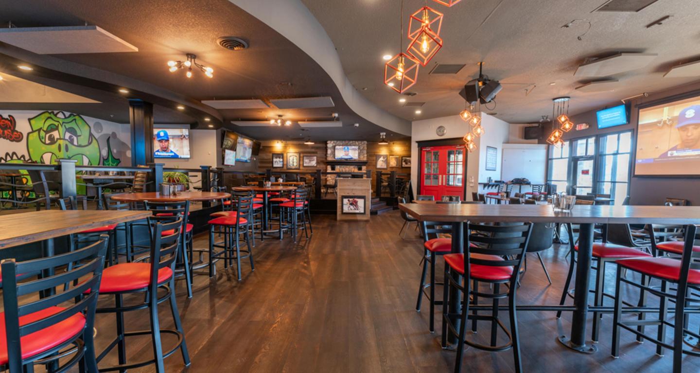 Cozy restaurant interior with wooden floors, red cushioned chairs, and warm lighting.