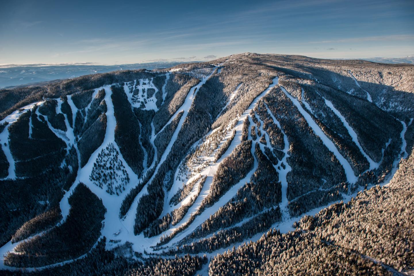 Snow-covered mountain with ski slopes under a clear blue sky.